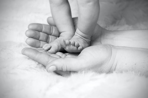 child's feet standing on adult's open hands